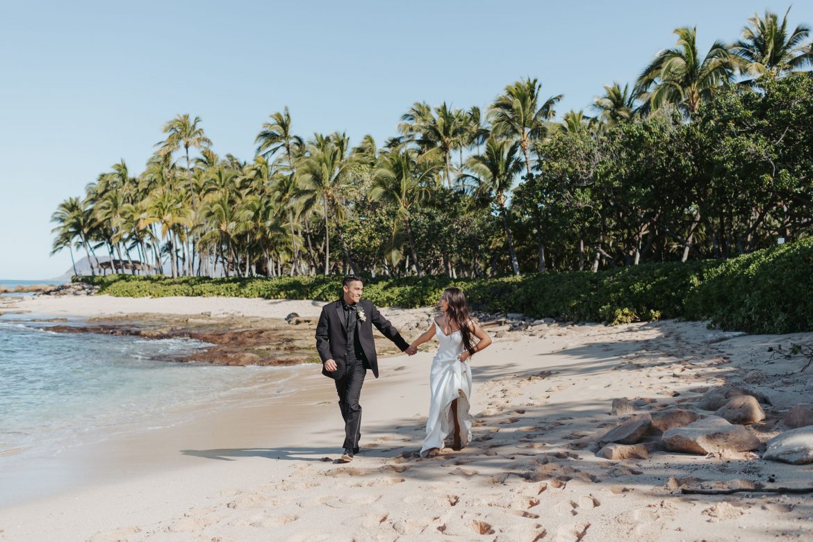 Bride and Groom holding hands running on the beach in hawaii beach wedding by melissa meyer